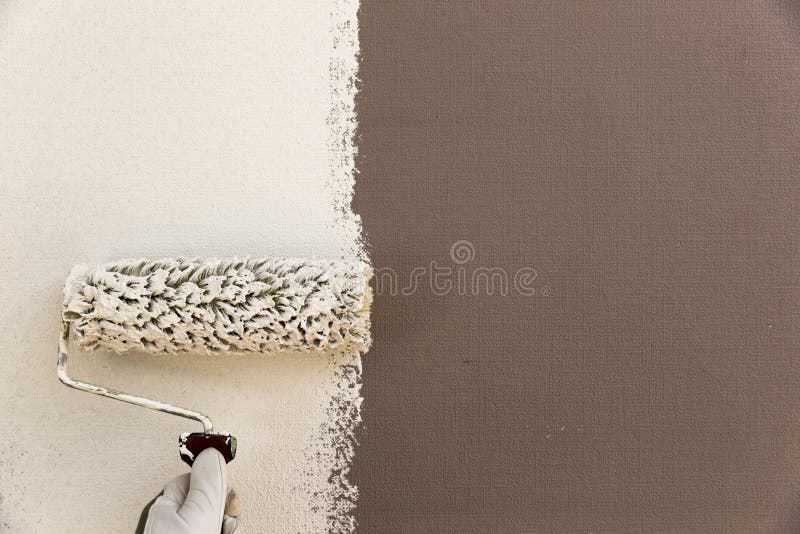 Blanco de la pared de la pintura de la mano del ` s del decorador con el rodillo