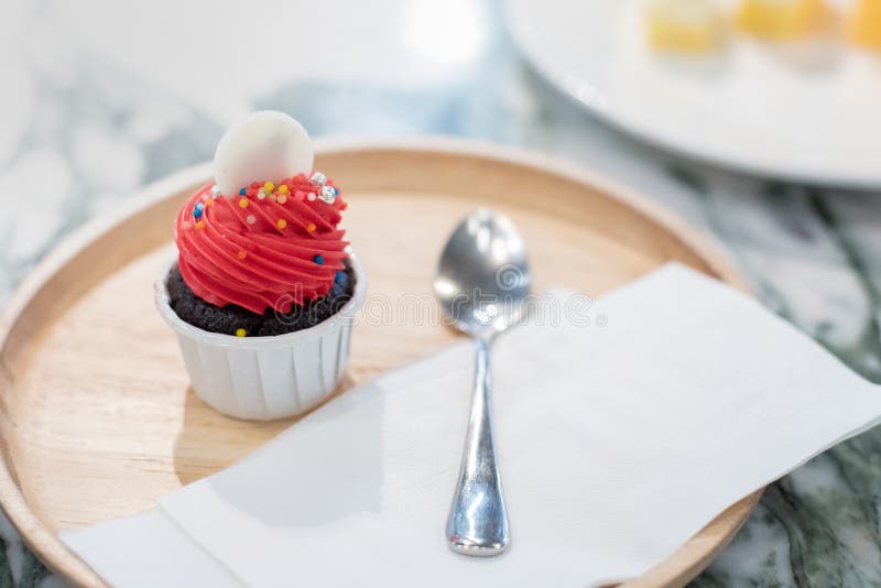 Blanco rojo y marrón de la mini torta de la magdalena del círculo en el top en la taza blanca placa de madera con la cuchara y el fotos de archivo libres de regalías Blanco rojo y marrón de la mini torta de la magdalena del círculo en el top en la taza blanca placa de madera con la cuchara y el fotos de archivo libres de regalías