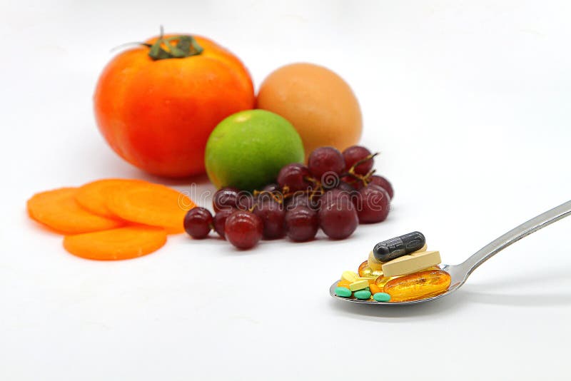 Blandade vitaminer och näringsrika tillägg i portionsked på färgrik fruktbakgrund för suddighet royaltyfria bilder Blandade vitaminer och näringsrika tillägg i portionsked på färgrik fruktbakgrund för suddighet royaltyfria bilder