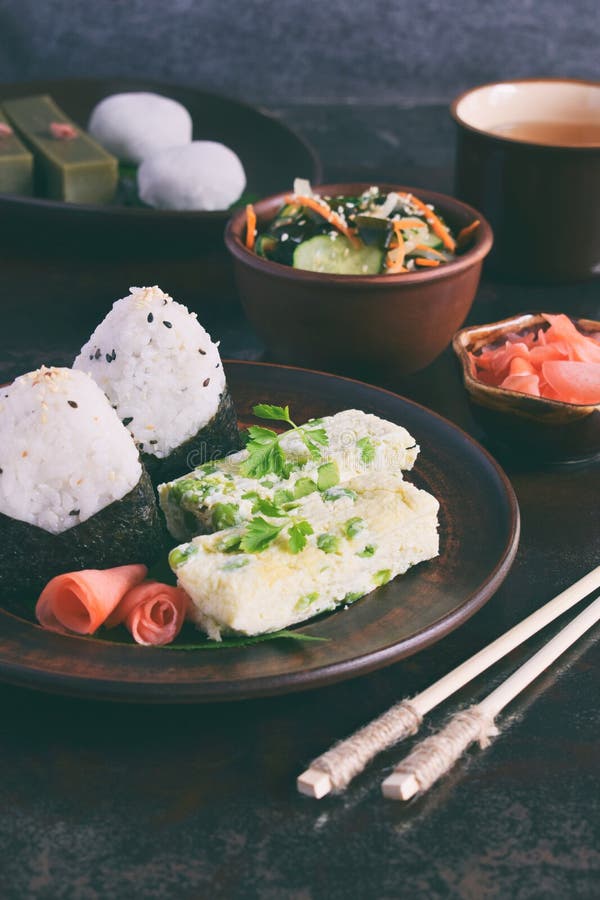 Blandning av japansk mat - ris klumpa ihop sig onigirien, omelett, ingef?ran, sallad f?r sunomonowakamegurka Traditionell efterr? arkivbilder Blandning av japansk mat - ris klumpa ihop sig onigirien, omelett, ingef?ran, sallad f?r sunomonowakamegurka Traditionell efterr? arkivbilder