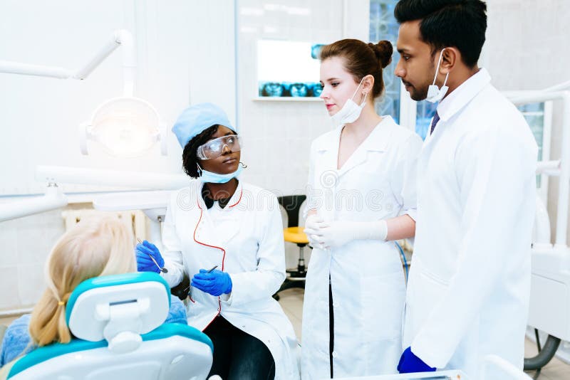 Blandras- tand- lag med patienten i tand- klinik Tand- vård- begrepp royaltyfri bild Blandras- tand- lag med patienten i tand- klinik Tand- vård- begrepp royaltyfri bild