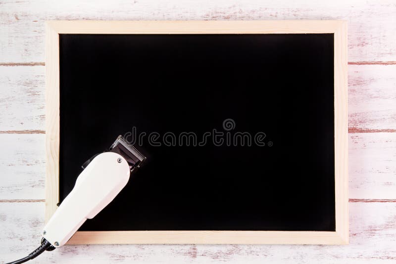 Blank blackboard and Clipper Barber on wooden table. Template mock up for adding your design and leave space beside frame for royalty free stock image