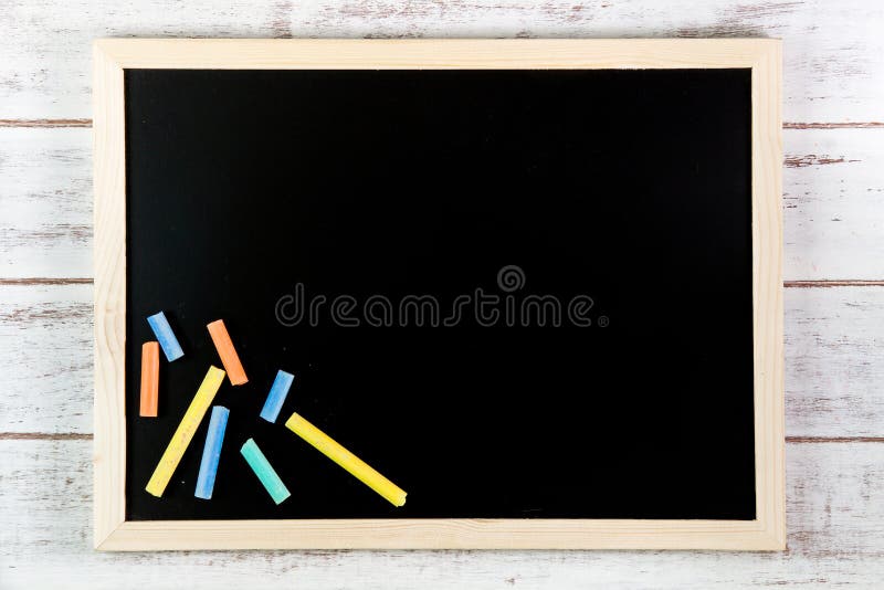 Blank blackboard and color chalk on wooden table. Template mock u royalty free stock photo
