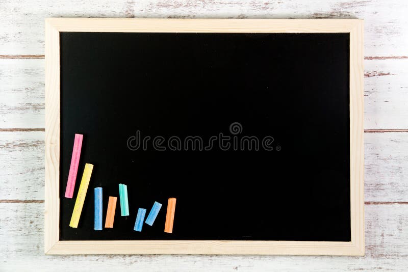 Blank blackboard and color chalk on wooden table. Template mock u royalty free stock photo