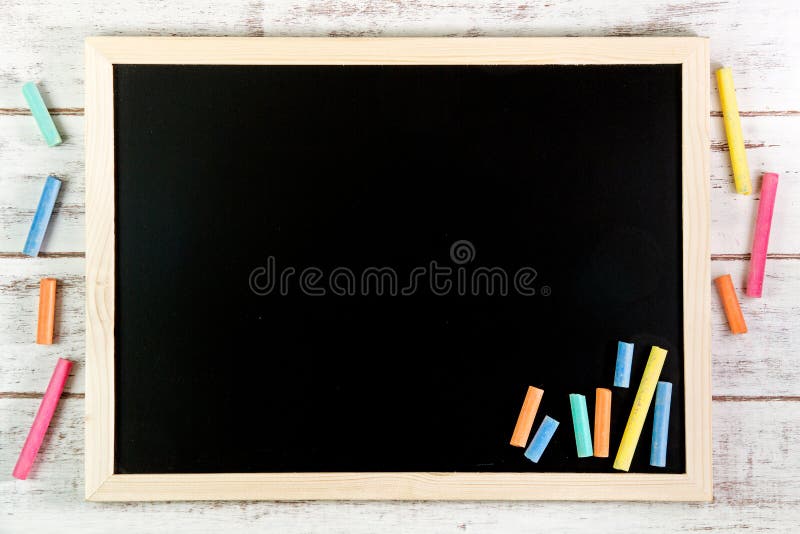 Blank blackboard and color chalk on wooden table. Template mock u stock photos