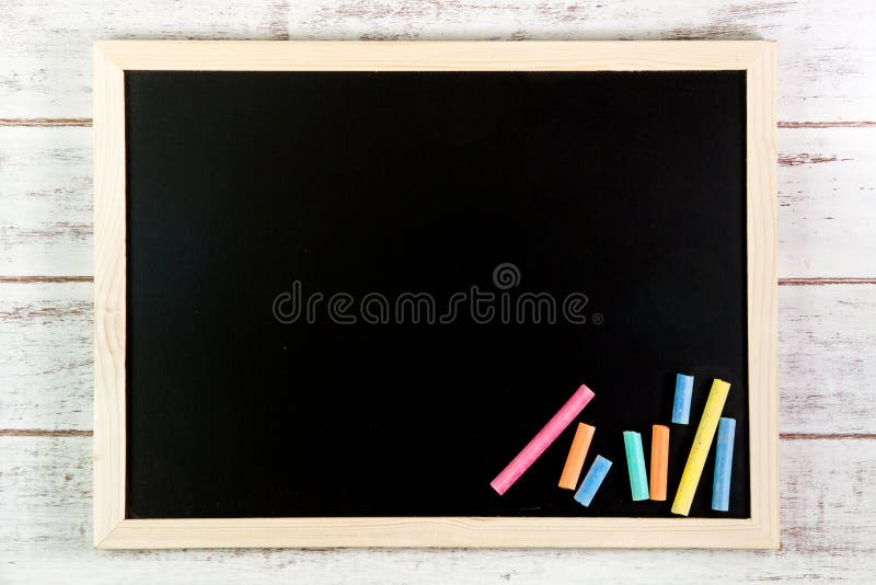 Blank blackboard and color chalk on wooden table. Template mock u stock image