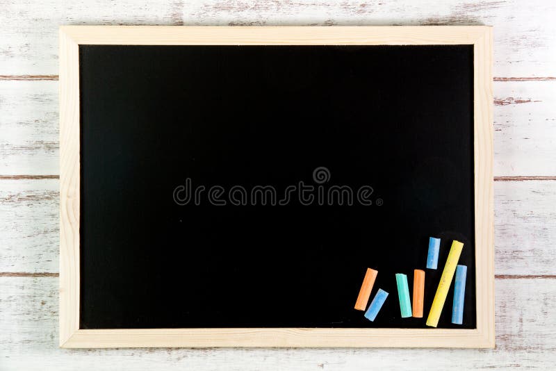 Blank blackboard and color chalk on wooden table. Template mock u royalty free stock images