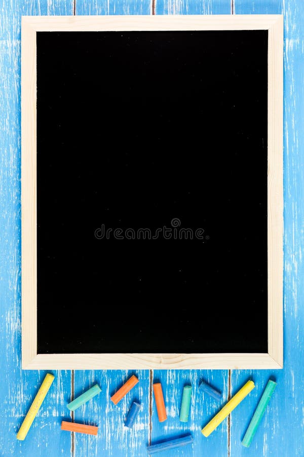 Blank blackboard and color chalk on wooden table. Template mock u royalty free stock photography