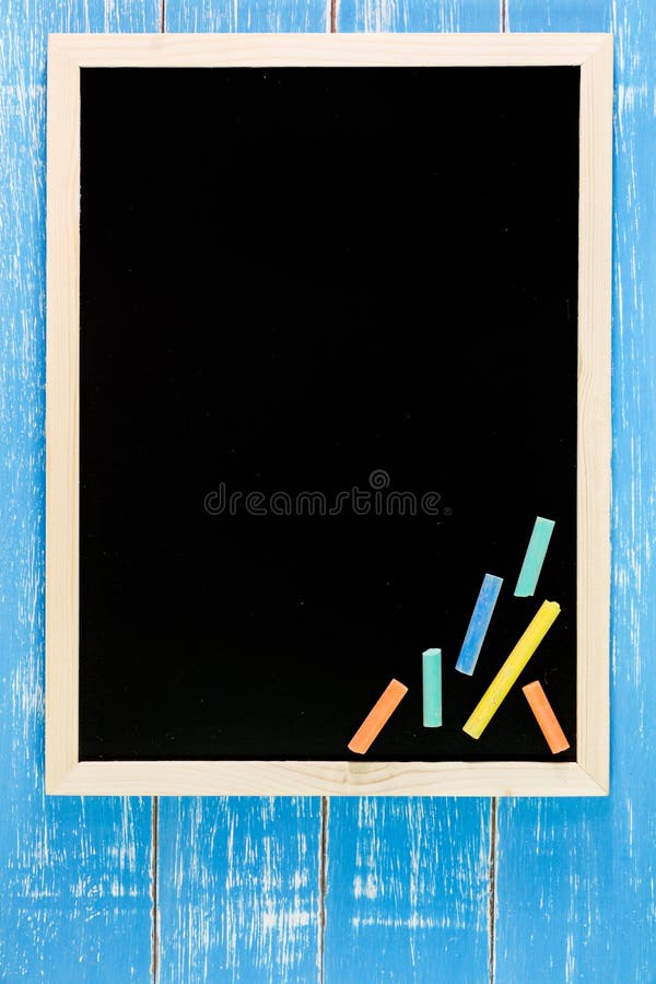 Blank blackboard and color chalk on wooden table. Template mock u stock photos