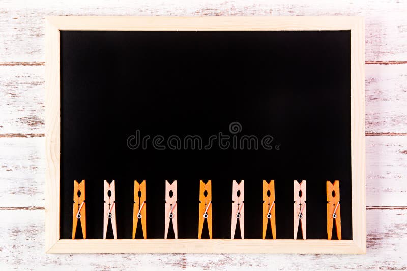 Blank blackboard and Orange clothes peg on wooden table. Template mock up for adding your design and leave space beside frame for royalty free stock photos