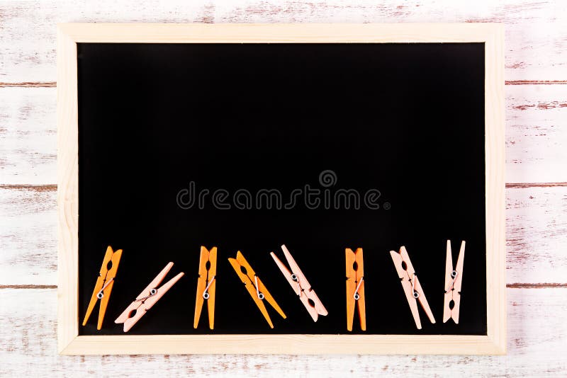 Blank blackboard and Orange clothes peg on wooden table. Template mock up for adding your design and leave space beside frame for stock image