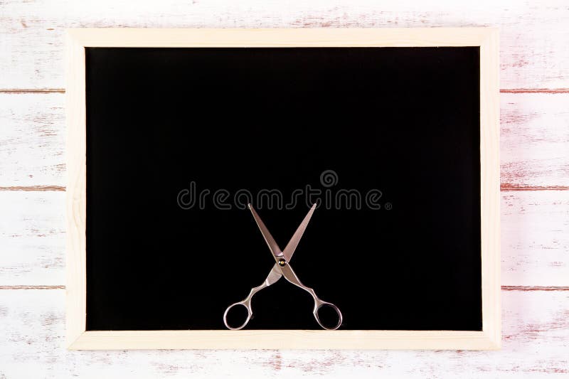 Blank blackboard and scissors hairdresser on wooden table. stock images