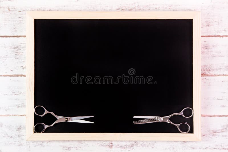Blank blackboard and scissors hairdresser on wooden table. stock images