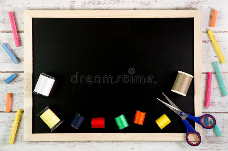Blank blackboard and sewing threads on wooden table. Template mock up for adding your design and leave space beside frame for royalty free stock photo