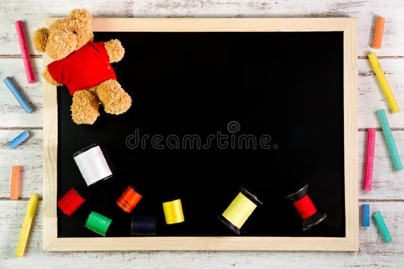 Blank blackboard and sewing threads on wooden table. Template mock up for adding your design and leave space beside frame for stock photography