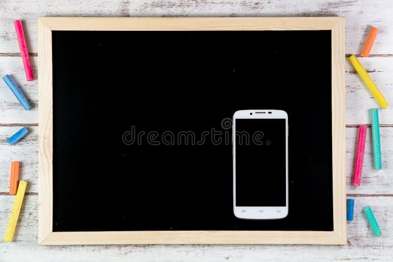 Blank blackboard and smart phone on wooden table. Template mock u stock photo