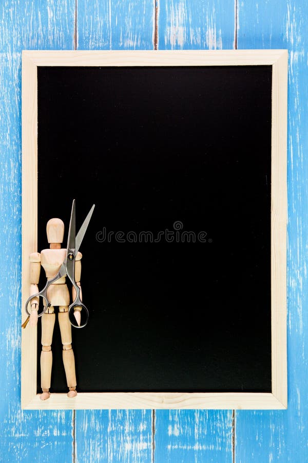 Blank blackboard and wooden puppet holding scissors hairdresser royalty free stock photography