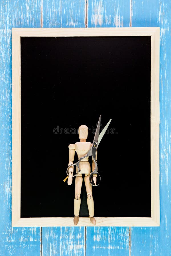 Blank blackboard and wooden puppet holding scissors hairdresser stock image
