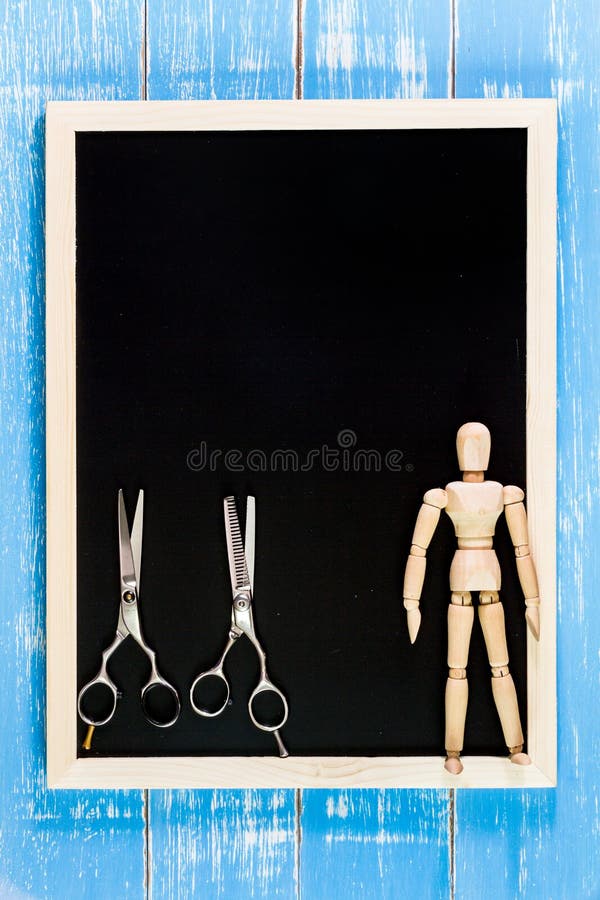 Blank blackboard and wooden puppet holding scissors hairdresser stock photo