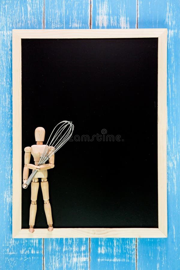 Blank blackboard and wooden puppet holding whisk egg on wooden t royalty free stock image