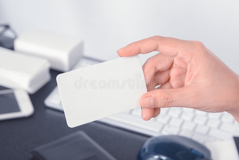 Blank Business Card Mock Up In Hand On Blurre Office Desk