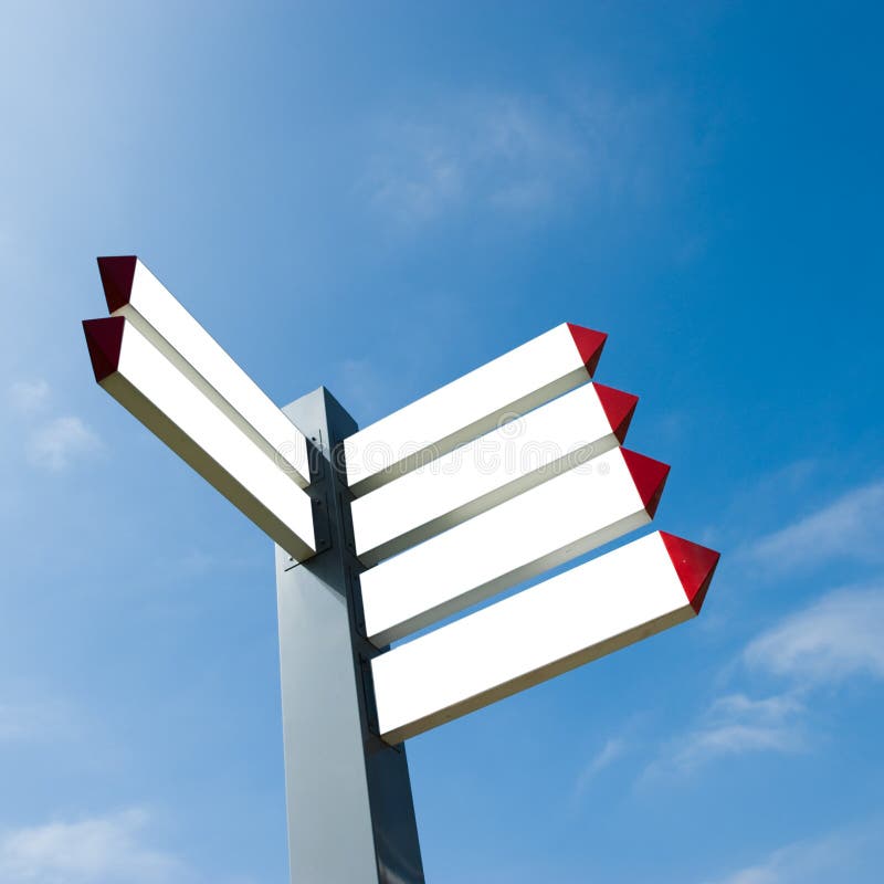 Blank directional arrow sign against blue sky.