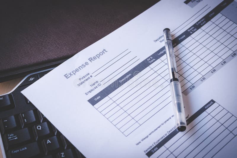 Blank Expense Report on Black Keyboard and Brown Leather Notebook on Pine Desk royalty free stock photos