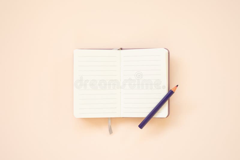 Blank lined note pad with colored pencil on pink desk background. top view. studio shot