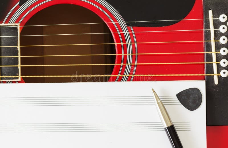 Blank music notebook page with copy-space, on red guitar with six strings. With pen and black guitar pick. Musical education stock images Blank music notebook page with copy-space, on red guitar with six strings. With pen and black guitar pick. Musical education stock images