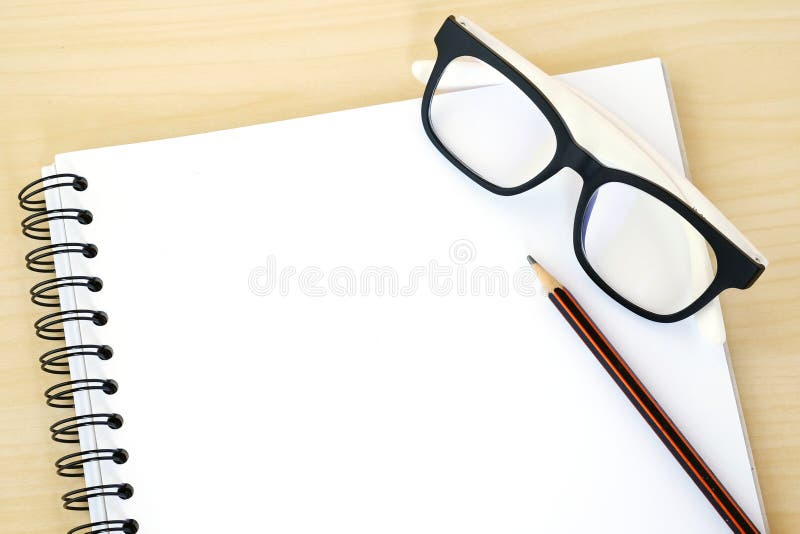 Blank note book, eye glasses and pencil on wood background