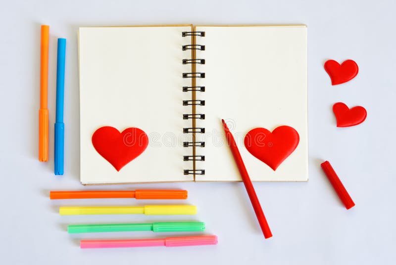 Blank notepad with multicolored felt-tip pens and red hearts on a white background. Template for Valentine`s Day greetings. stock photo Blank notepad with multicolored felt-tip pens and red hearts on a white background. Template for Valentine`s Day greetings. stock photo