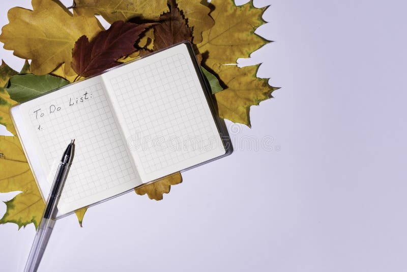Blank notepad for writing To-do list, pen and autumn colorful leaves on white background, flat lay, copy space, top view, corner location. To-do list concept in autumn months