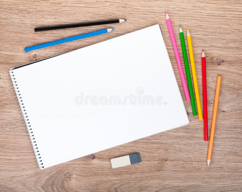 Blank paper and colorful pencils on the wooden table
