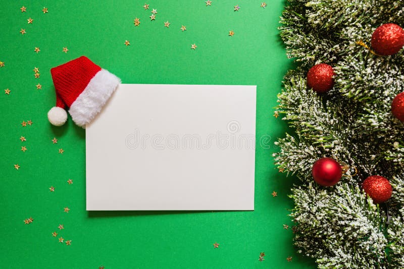Blank of paper with red Santa hat, christmas tree branches on green background with confetti. new year concept. Greeting card,. Paper blank with Santa hat royalty free stock photography Blank of paper with red Santa hat, christmas tree branches on green background with confetti. new year concept. Greeting card,. Paper blank with Santa hat royalty free stock photography
