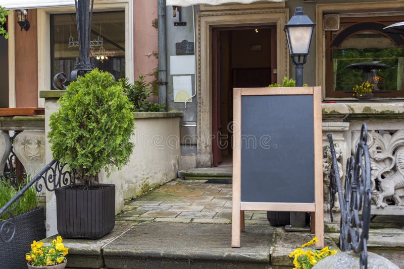 Blank restaurant shop sign or menu board near the entrance to restaurant. Cafe menu on the street. Blackboard sign mockup in front