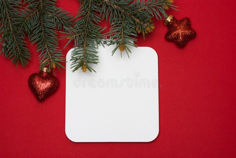 Blank sheet of notebook on a twisted spring against the background of a branch of a christmas tree on a red background