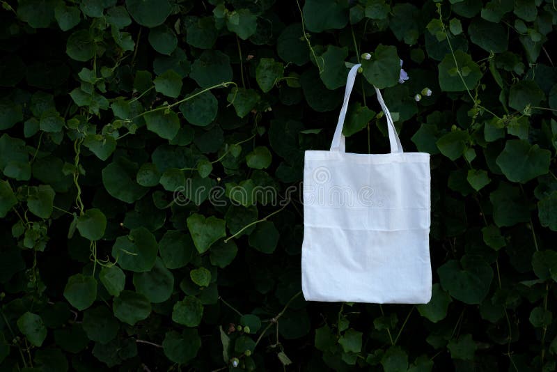 Blank white fabric cloth bag tote at green bush trees foliage Background