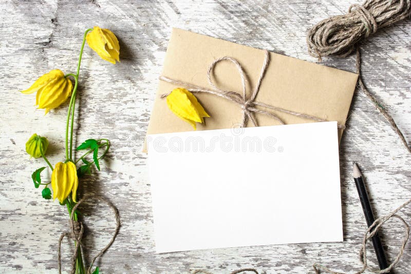 Blank white greeting card and envelope with yellow autumn flowers and pencil