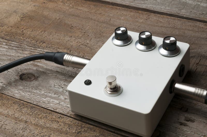 A Blank White Guitar Pedal with Vintage Knobs and Plugged Jacks on the