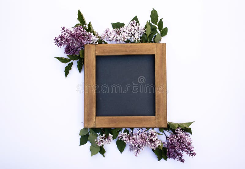 A blank wooden blackboard frame mock-up on a white background with lilac flowers and leaves