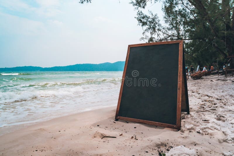 blank wooden sign on beach. Black Board for writing menu chalk on white sand on beach on tropical exotic island