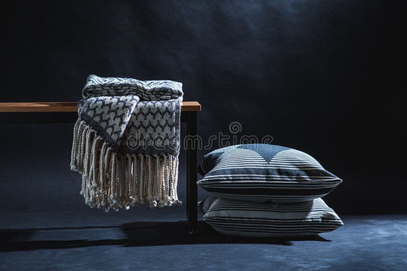 Blanket on Bench and Pillows on Floor in Dark Room Stock Photo Image