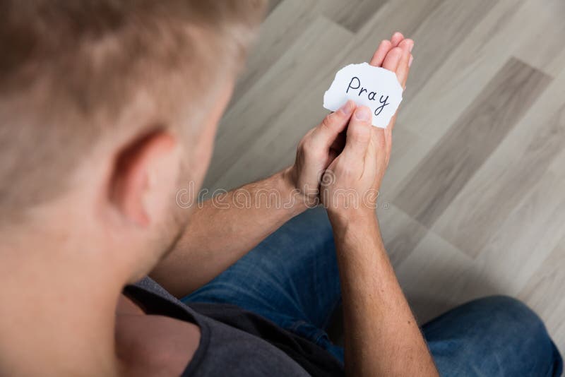 Man Holding A Piece Of Paper With The Text Pray In His Hand. Man Holding A Piece Of Paper With The Text Pray In His Hand