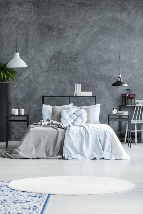 Pastel blue bedding and knot cushion on a gray bed in bedroom interior with round rug and metal lamps. Pastel blue bedding and knot cushion on a gray bed in bedroom interior with round rug and metal lamps