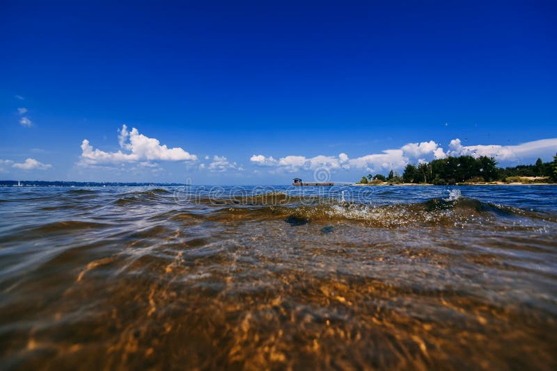Blauer klarer Himmel mit weißen Wolken über Wasser am Sommertag und Strand mit Wellen lizenzfreie stockbilder Blauer klarer Himmel mit weißen Wolken über Wasser am Sommertag und Strand mit Wellen lizenzfreie stockbilder