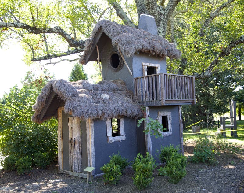 A fancifully crafted tree house sits in a forest courtyard. A fancifully crafted tree house sits in a forest courtyard.