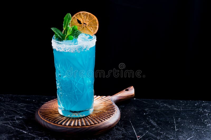 Blauwe die cocktail met ijs, met munt en plak van droge die sinaasappel in mooi wordt verfraaid glassm op zwarte achtergrond word royalty-vrije stock afbeeldingen Blauwe die cocktail met ijs, met munt en plak van droge die sinaasappel in mooi wordt verfraaid glassm op zwarte achtergrond word royalty-vrije stock afbeeldingen