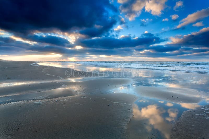 Blauwe die hemel cloudscape in Noordzee wordt weerspiegeld