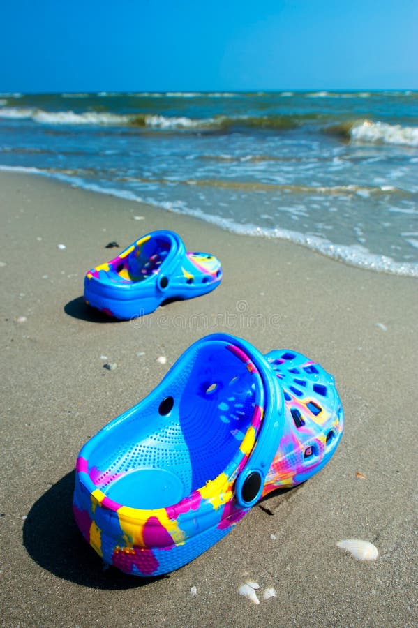 Blauwe strandpantoffels op zandig strand stock afbeelding Blauwe strandpantoffels op zandig strand stock afbeelding