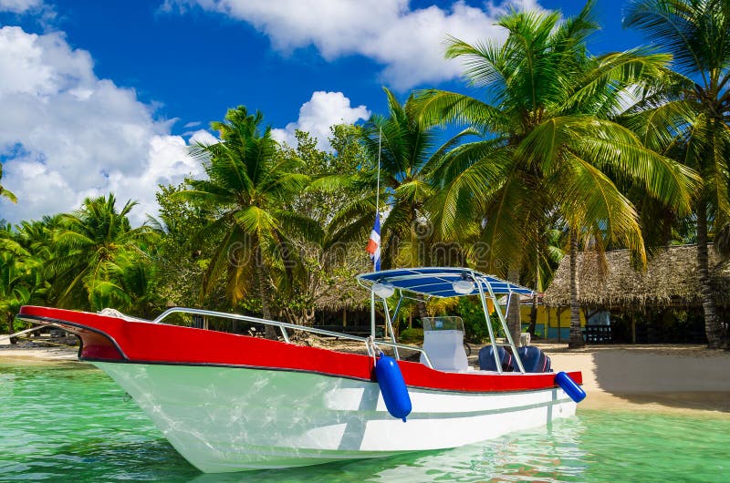 Blauwe, witte, rode boot op azuurblauw water onder palmen